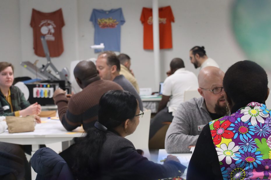 Omnia Makerspace Hackathon-tapahtuman osallistujia keskustelemassa toisilleen pöytien ympärillä.