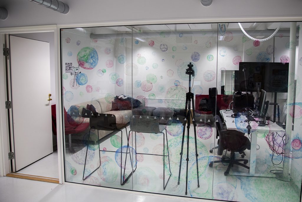 Omnian Makerspacen studio, jossa sohva, tuoleja, tietokoneita, näyttö sekä kuvaustekniikkaa.